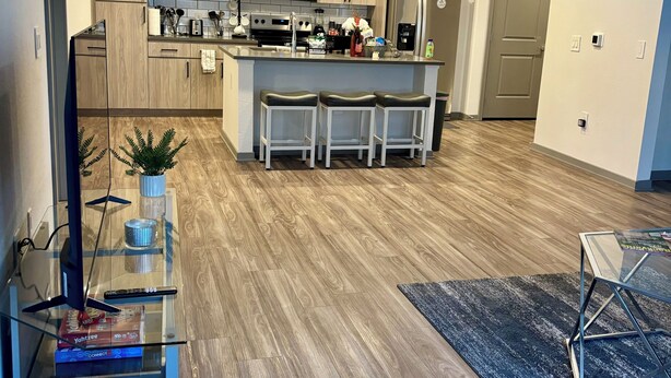 A modern kitchen with wooden cabinets, a central island with bar stools, a microwave, and a refrigerator. - Brand-New Build-Luxury 2BR Retreat-Resort Pool -Travel Nurse Friendly-Buckeye AZ (Buckeye)
