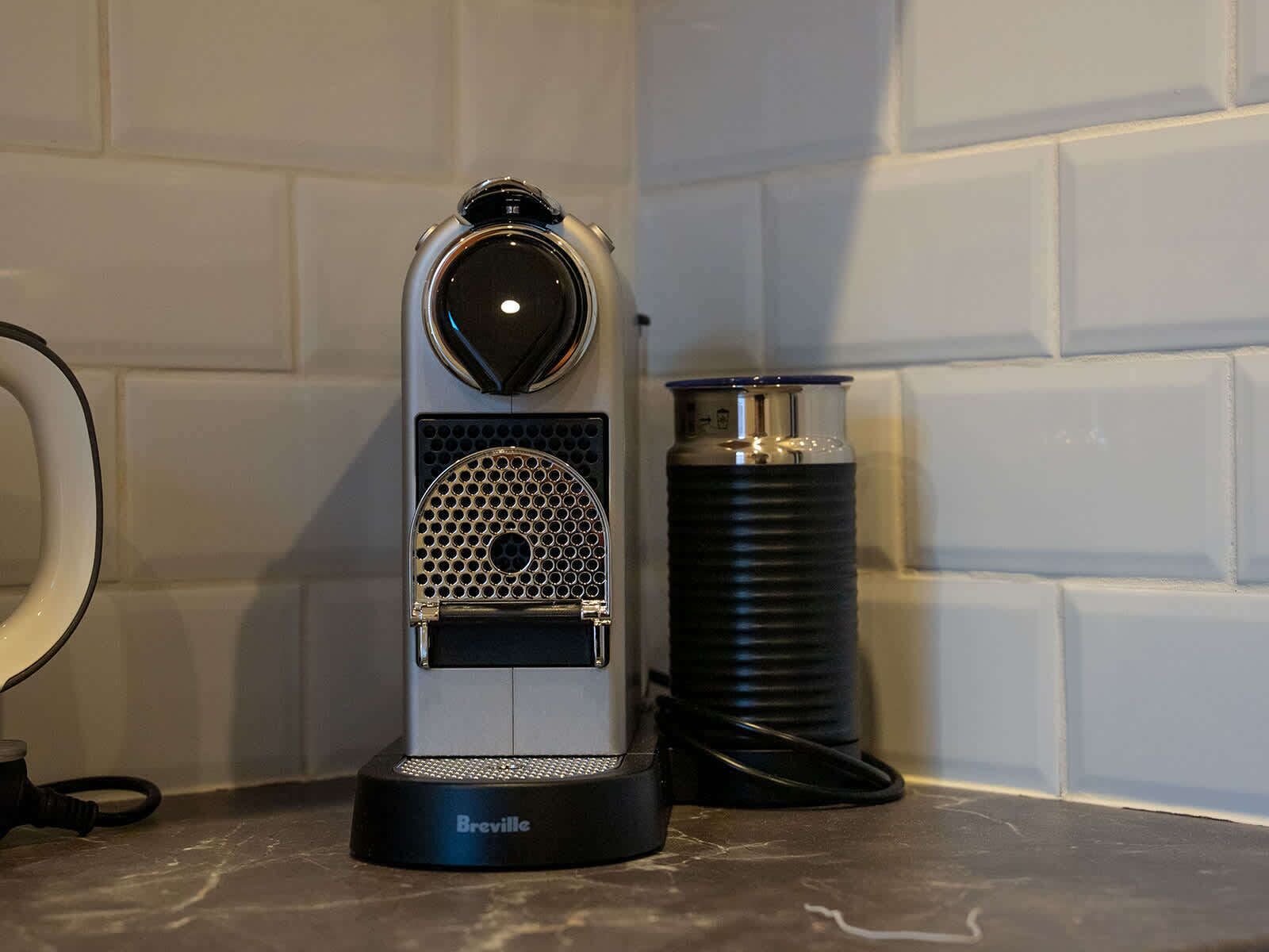A Breville espresso machine with a water tank and a power cord.