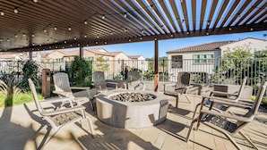 Eine Terrasse im Freien mit Feuerstelle, Liegestühlen und einer Pergola mit Lichterketten.