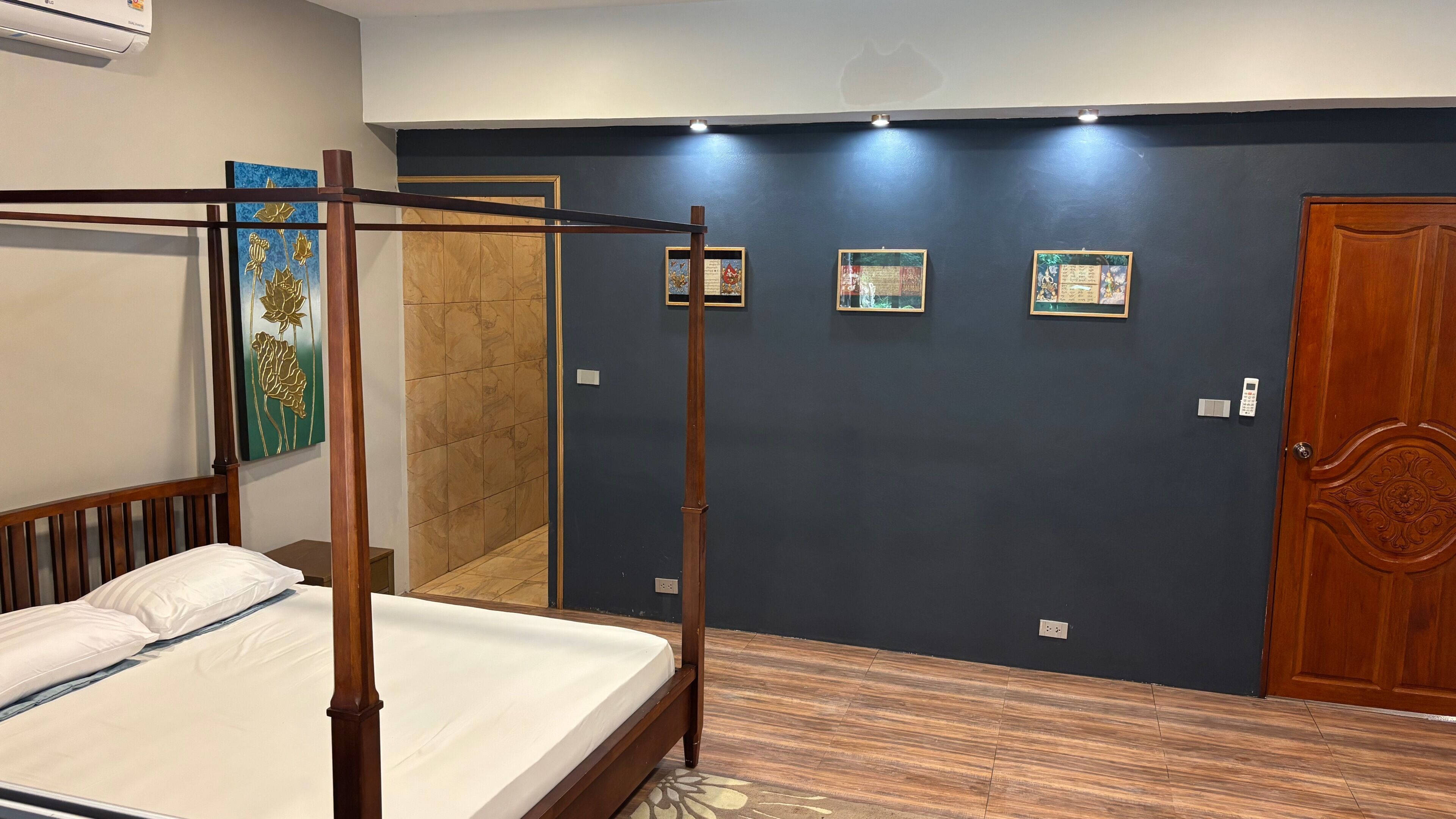 Un dormitorio con cama con dosel, una puerta de madera y una pared con cuadros.