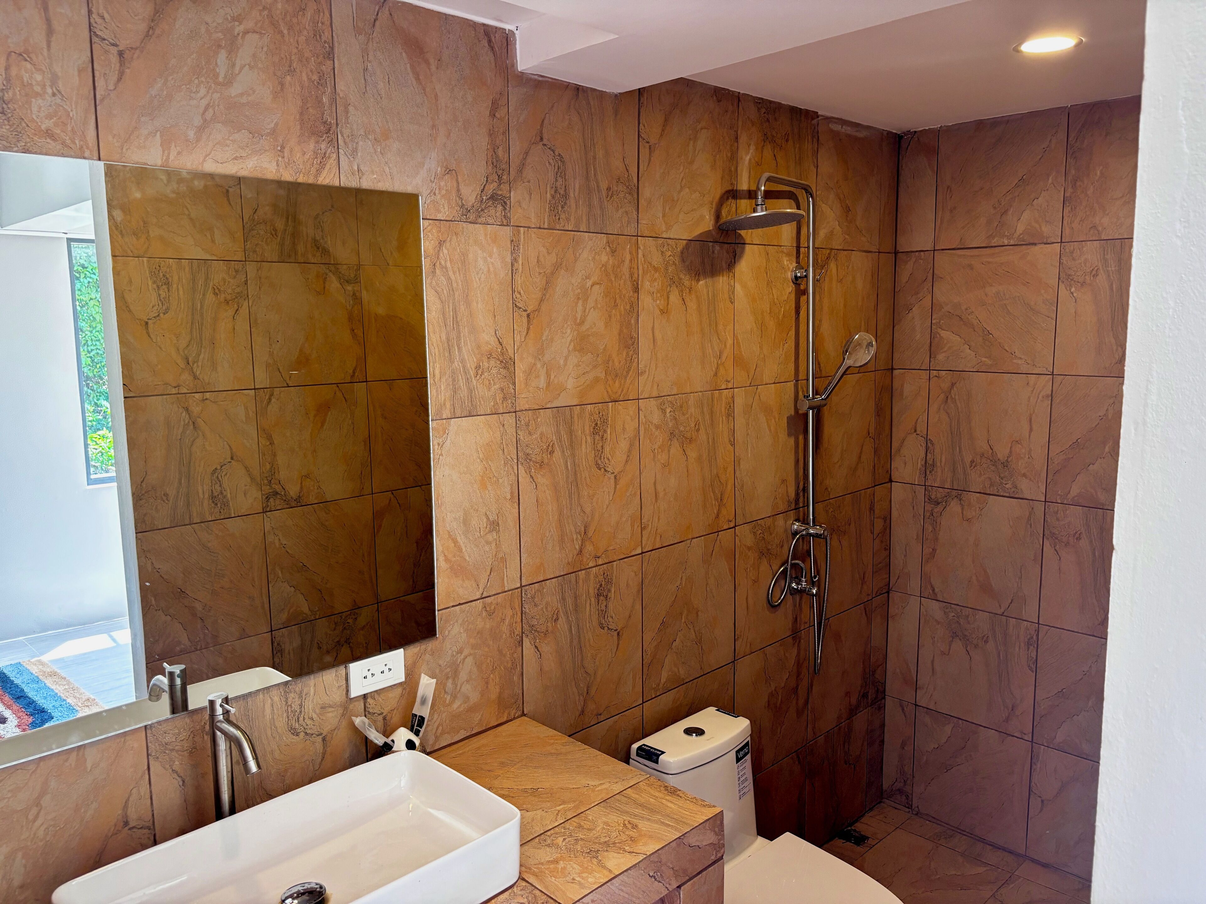Un baño con ducha, lavamanos y espejo.