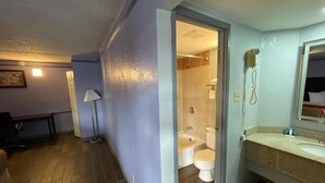 A bathroom with a bathtub, toilet, and a hairdryer on the wall. - Kings Inn (Memphis)