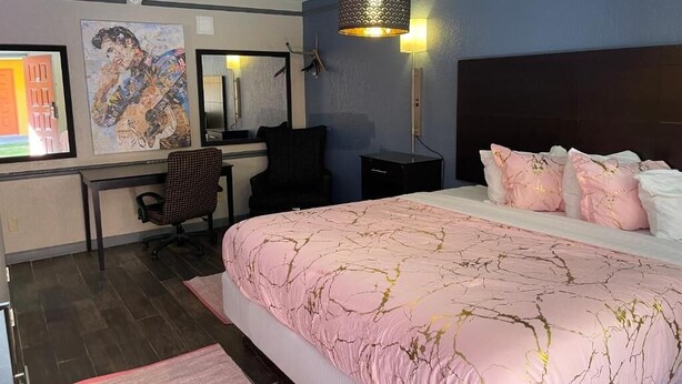 A hotel room with a bed, desk, chair, and a large mirror. - Kings Inn (Memphis)
