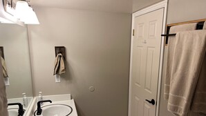 A bathroom with a white sink, two faucets, a mirror, a towel rack, and a door. - Charming 1-bedroom King condo in Park City perfect for your getaway (Park City)