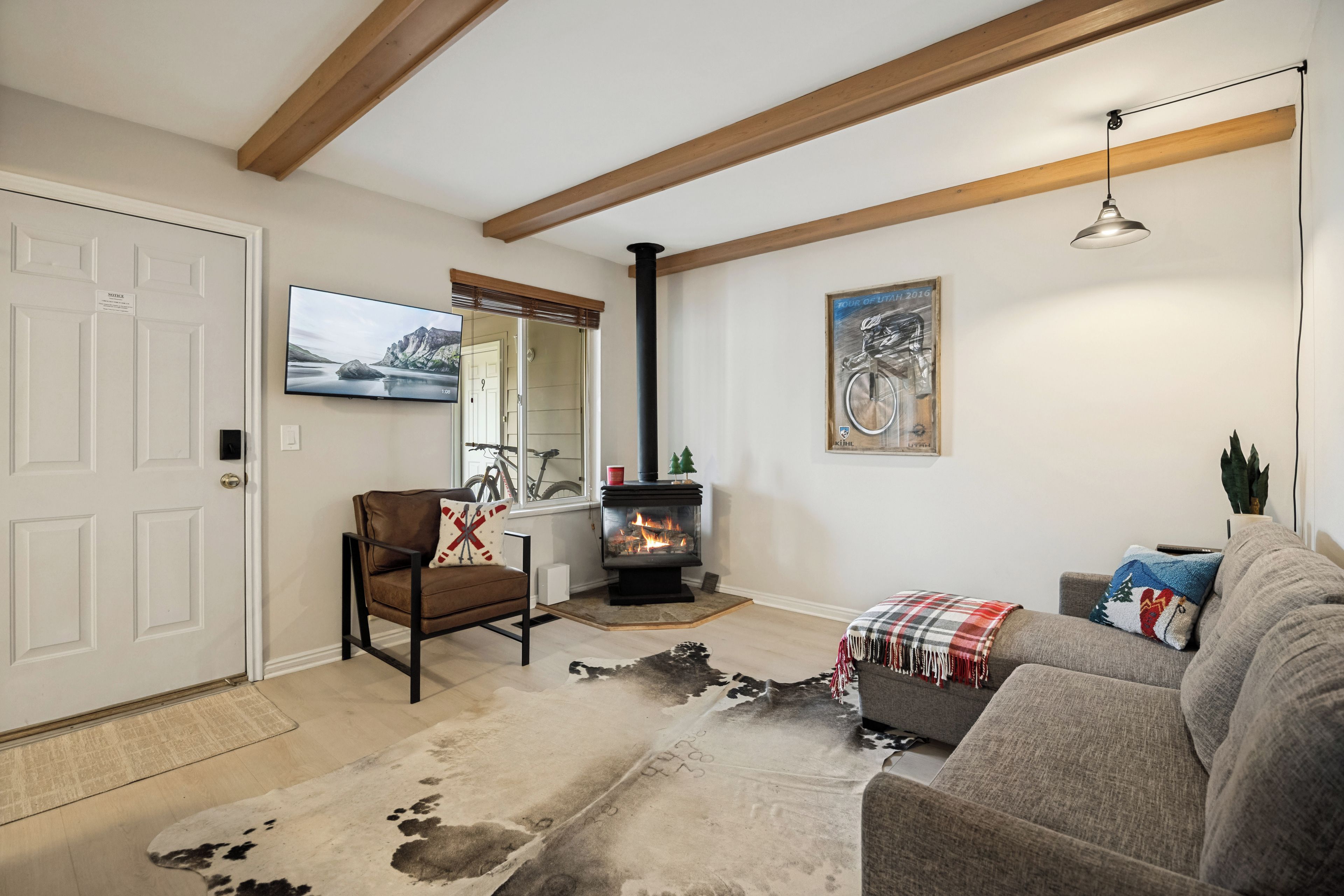 A living room with a fireplace, a sofa, a chair, a television, and a mounted picture.