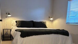 A bedroom with a bed, two bedside lamps, a ceiling fan, and a window with blinds. - Charming 1-bedroom King condo in Park City perfect for your getaway (Park City)
