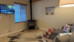 A living room with a fireplace, a television mounted on the wall, and a sofa with a blanket. - Charming 1-bedroom King condo in Park City perfect for your getaway (Park City)