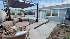 En terrasse med havemøbler, en pergola og et haveareal.