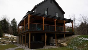 Et toetagers hus med en overdækket veranda, en stenvæg og et udendørs siddeområde.