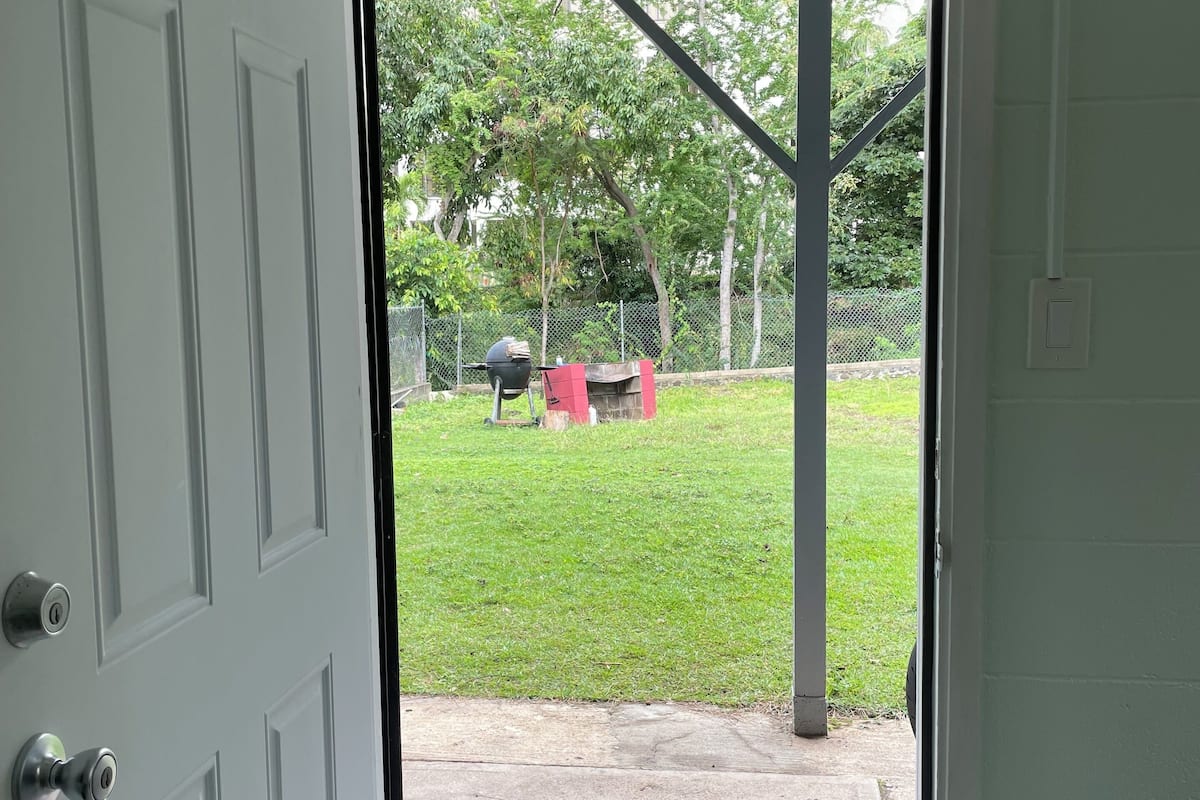 A doorway leading to a covered outdoor area with a grill and barbecue equipment.