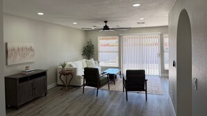Un salon spacieux avec un canapé blanc, deux fauteuils, une table basse et un meuble en bois.
