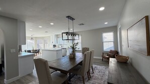 Une cuisine moderne avec des meubles blancs, un îlot central et un luminaire suspendu.
