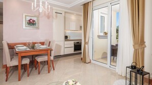 Un'elegante zona pranzo moderna con un tavolo in legno apparecchiato per quattro persone, un lampadario e una cucina sullo sfondo.