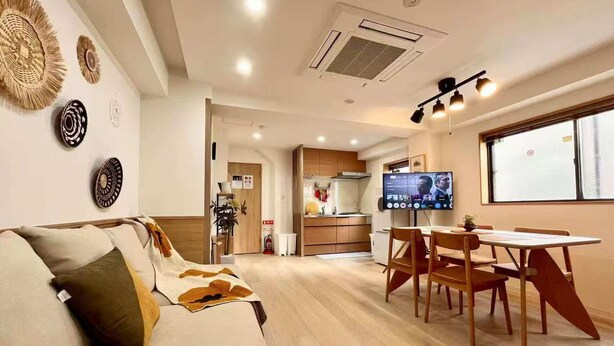 A modern living room with a sofa, dining table, and TV. - Raku6 Designer-style Japanese-Western Two-bedroom Ryokan / 15 mins to Shinjuku, (Nakano-ku City)