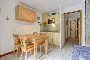 Eine kompakte Küche mit Holzausstattung, einem Esstisch mit Stühlen und einer Mikrowelle.