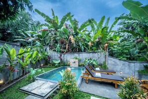 A pool area with lounge chairs and a stone wall.