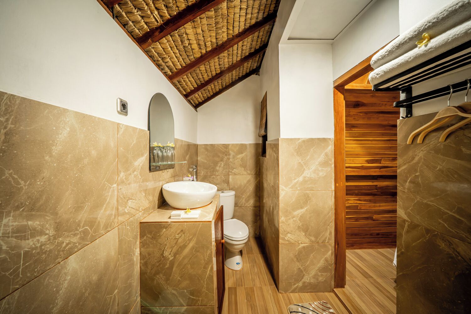 Een badkamer met een marmeren wastafel, toilet en een houten trap.