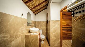 Een badkamer met een marmeren wastafel, toilet en een houten trap.