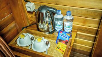 Un intérieur en bois avec un plateau contenant une théière, deux tasses à thé, deux soucoupes, deux bouteilles d’eau et un paquet de collations.