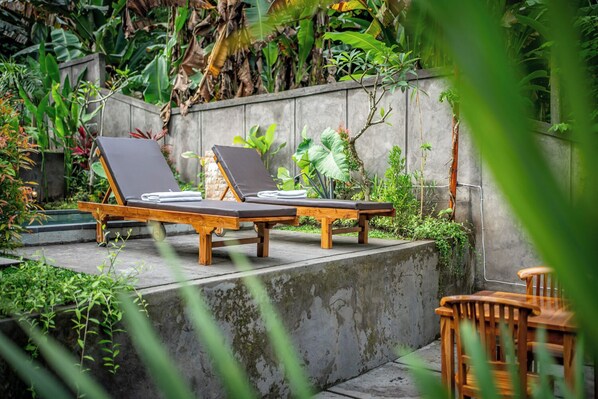 A garden with two wooden lounge chairs and a small table.