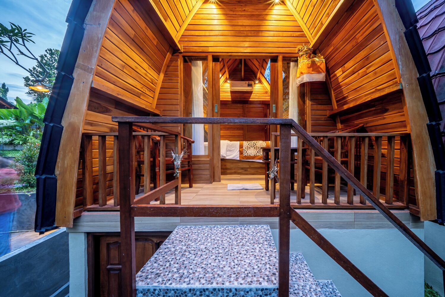 A wooden cabin with a staircase leading to a covered porch area.