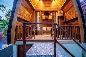A wooden cabin with a staircase leading to a covered porch area.