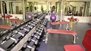 A gym with rows of dumbbells, benches, and exercise balls.