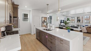 Una cocina moderna con una isla grande, electrodomésticos de acero inoxidable e iluminación colgante.