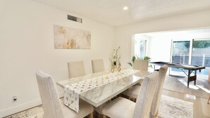 A dining area with a marble table, cushioned chairs, and a decorative table runner. - Spacious Luxury Oasis Getaway w/pool 15 mins from beach (Fort Lauderdale)