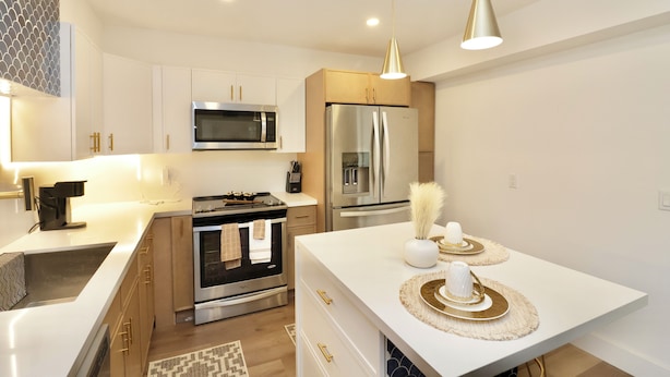 A modern kitchen with white cabinetry, stainless steel appliances, and a central island with decorative items. - Spacious Luxury Oasis Getaway w/pool 15 mins from beach (Fort Lauderdale)