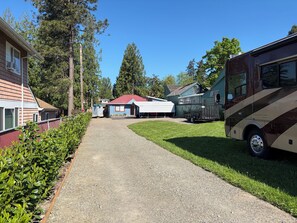 A gravel driveway leading to a row of RVs and mobile homes, with a clear sky above. - Completely Updated Darling Home (Milwaukie)