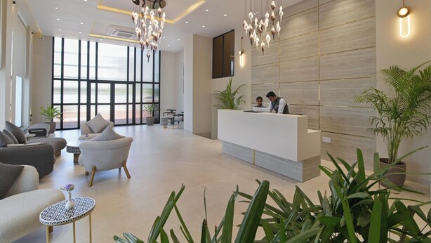 A modern hotel lobby with a reception desk, seating area, and large windows. - Amber-A Unit of Sayaji Hotels (Bhopal)