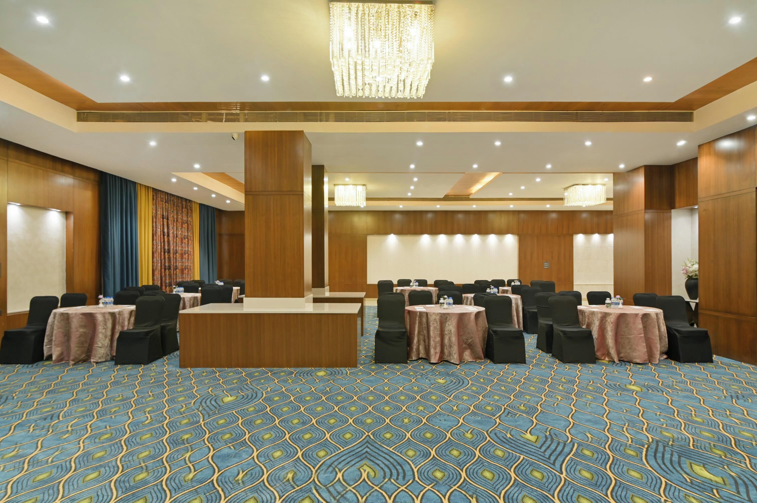 A conference room with a large table, multiple chairs, and a patterned carpet.