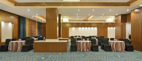 A conference room with a large table, multiple chairs, and a patterned carpet.
