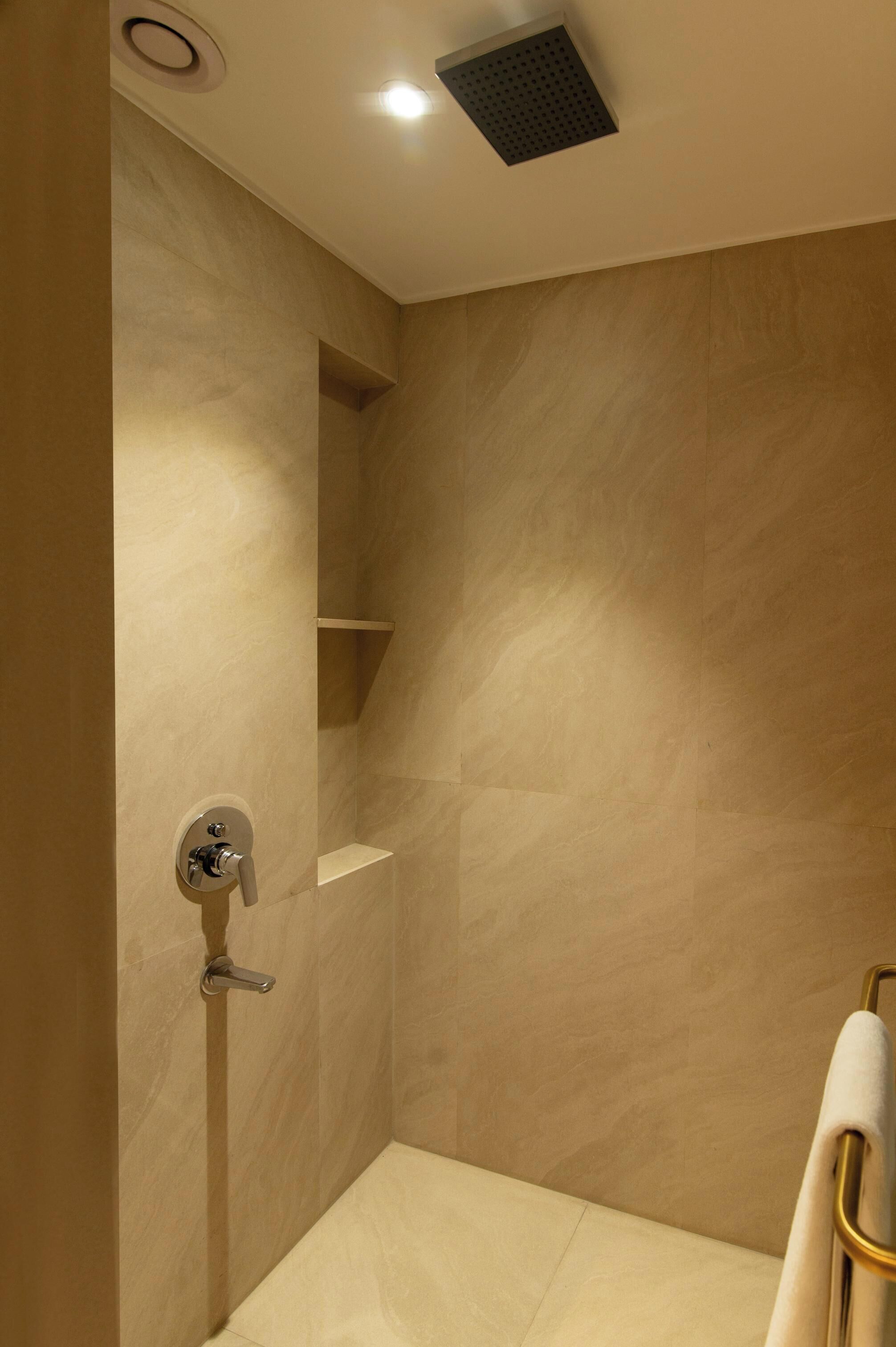 Een moderne badkamer met een douche, een handdoekhouder en een plank.