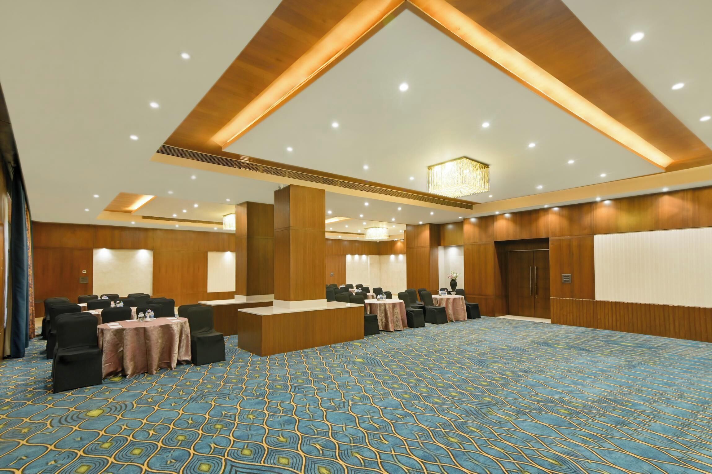 A conference room with a patterned carpet, wooden paneling, and a central podium.