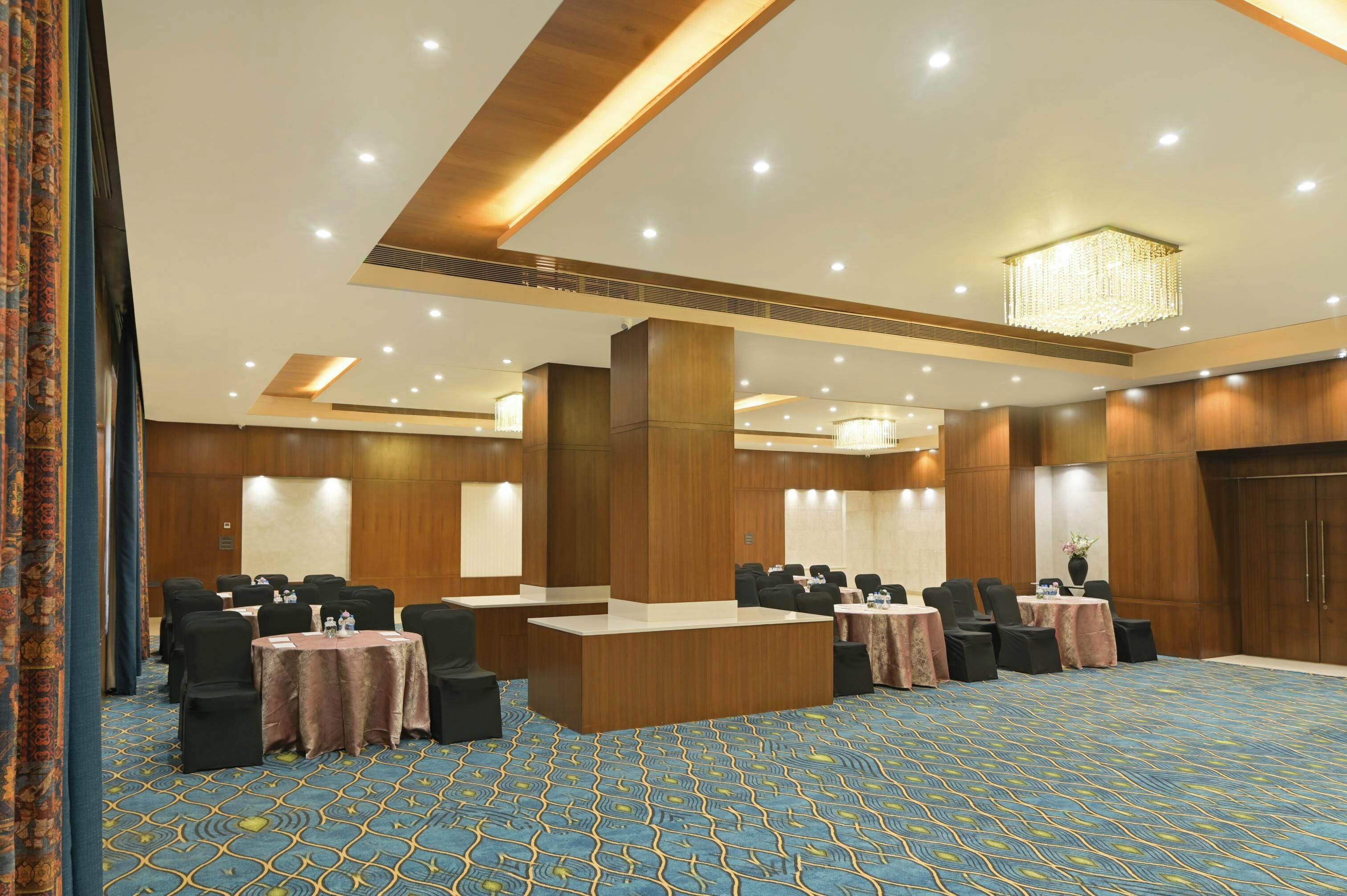A conference room with a wooden reception desk, round tables, and black chairs.