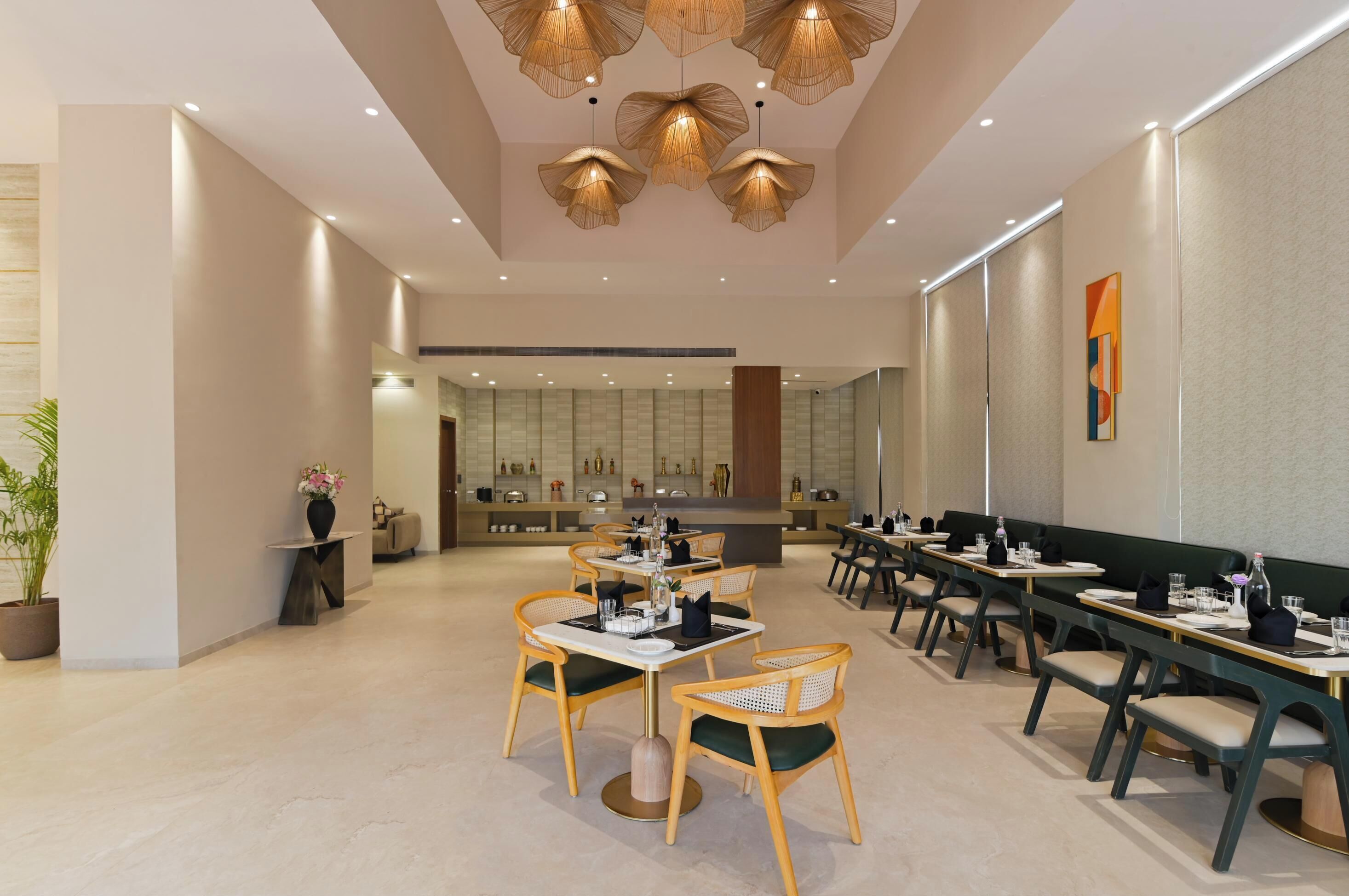 A modern restaurant with wooden chairs and tables, a central dining area, and a kitchen in the background.