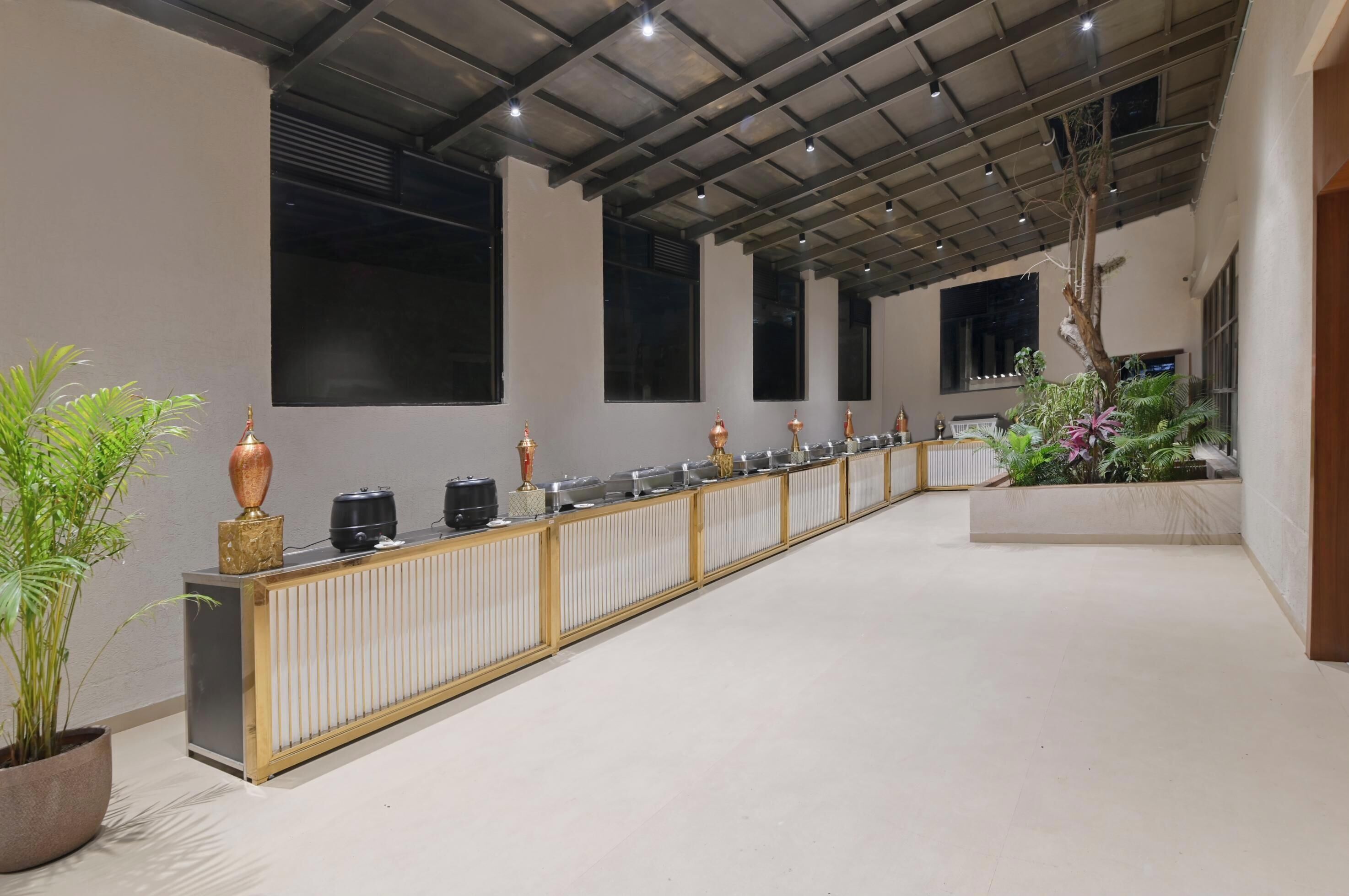 A long reception desk with a radiator, potted plants, and a row of black kettles.