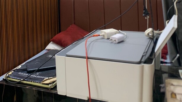 Une salle d’attente avec une pancarte indiquant « RÉCEPTION » sur le mur, un lit avec un oreiller rouge et un appareil médical posé sur une table.