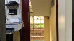 Un couloir étroit avec un ventilateur, une porte et une fenêtre donnant sur une clôture.