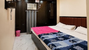A bedroom with a bed, a wall-mounted TV, an air conditioning unit, and a ceiling fan. - New Jay Radhe Krishan Residency (Varanasi)