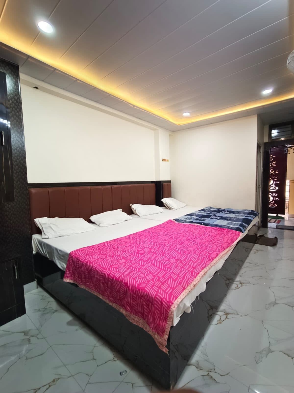 Ein Hotelzimmer mit einem großen Bett, einem Kopfteil und einem Marmorboden.