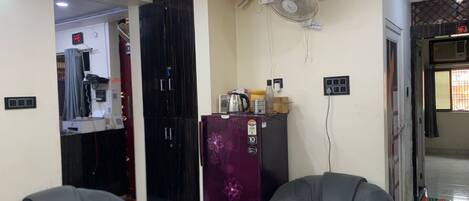 A living room with two grey armchairs, a purple refrigerator, and a ceiling fan.