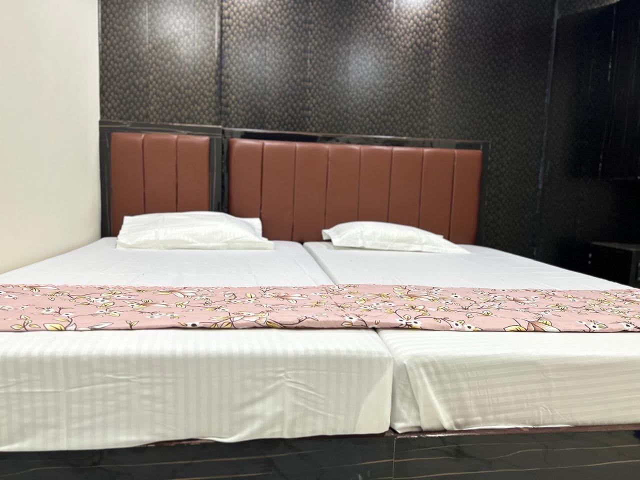 Una cama doble con una colcha estampada, un cabecero y una pared oscura al fondo.