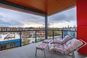 A balcony with lounge chairs and a view of a cityscape. - Sun-Filled 2BR Condo | Bright, Open, Near Event Center, Shops & Transit (Langley Township)
