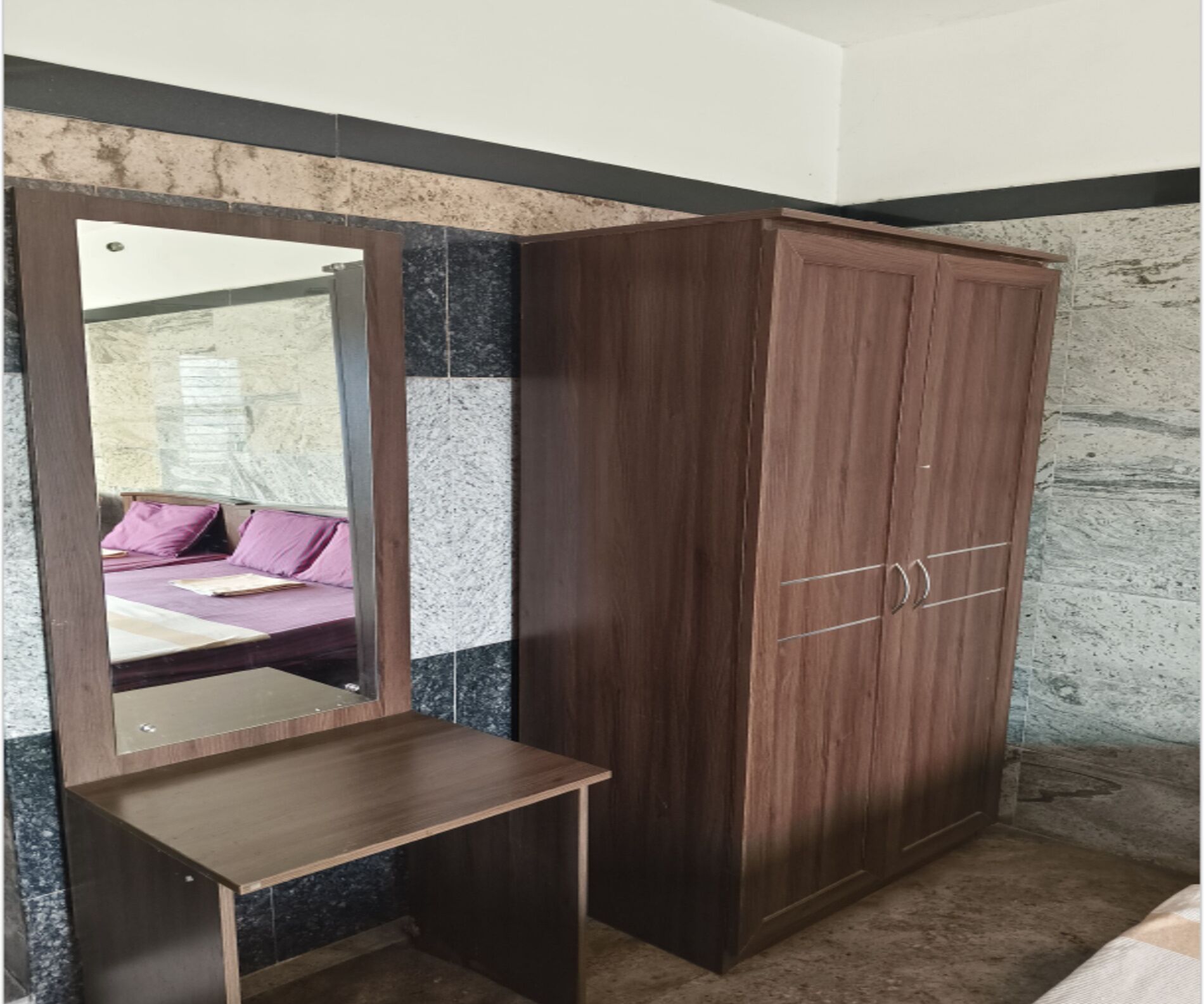Ein Schlafzimmer mit einem Holzschrank, einem Spiegel und einem Bett mit violetter Bettwäsche.
