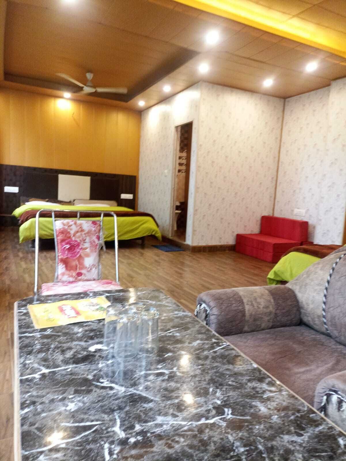 A hotel room with a marble reception desk, a bed with floral bedding, a red sofa, and a ceiling fan.