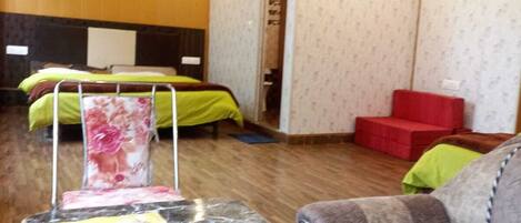 A hotel room with a marble reception desk, a bed with floral bedding, a red sofa, and a ceiling fan.