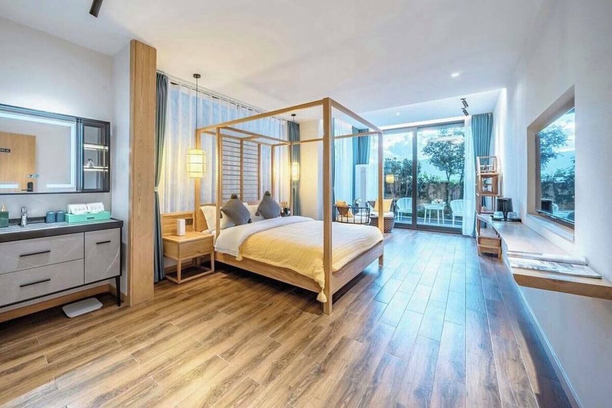 Un dormitorio espacioso con cama con dosel, tocador con espejo y un amplio ventanal con vistas al exterior.
